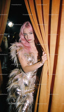 Model with Pink Hair in Feathered Gold Dress Behind Curtain