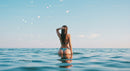 Woman in Bikini Relaxing in Calm Blue Ocean Under Clear Sky