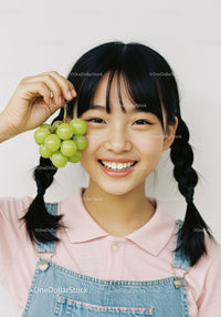 Young Girl Smiling and Holding Green Grapes in Bright Studio