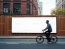 Urban cyclist passing a large blank billboard outdoors