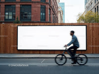 Urban cyclist passing a large blank billboard outdoors