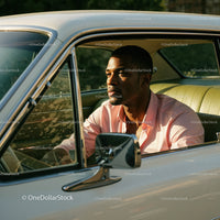 Young Man in Pink Shirt Sitting in Vintage Car on a Sunny Day
