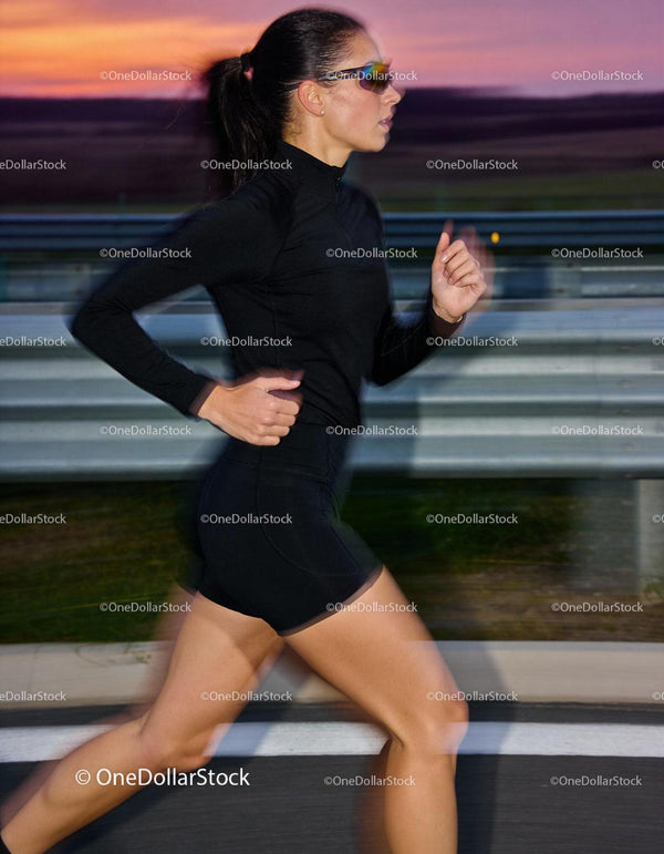 Athletic woman jogging outdoors during vibrant sunset