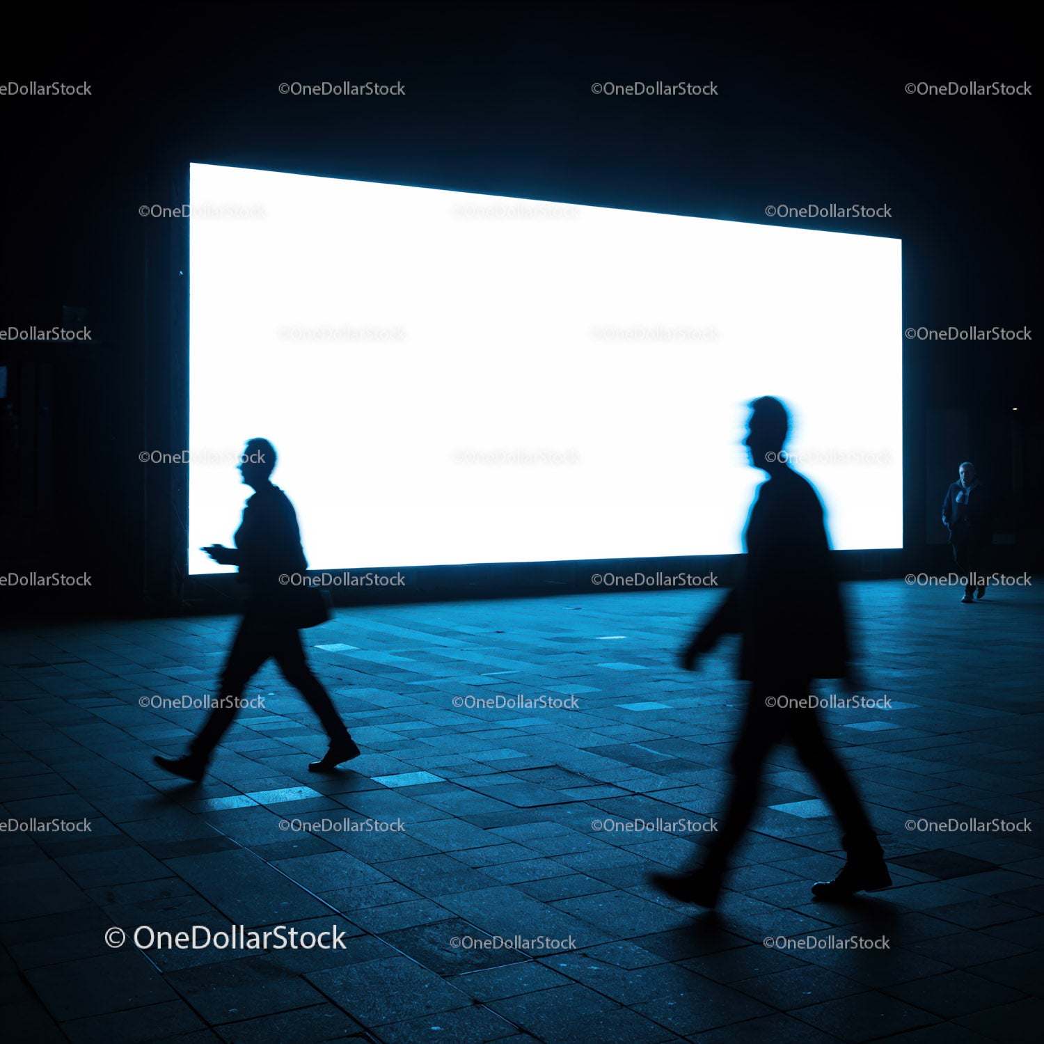 Silhouettes walking past bright urban billboard at night