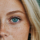 Close up of blue eye and blonde hair with freckles