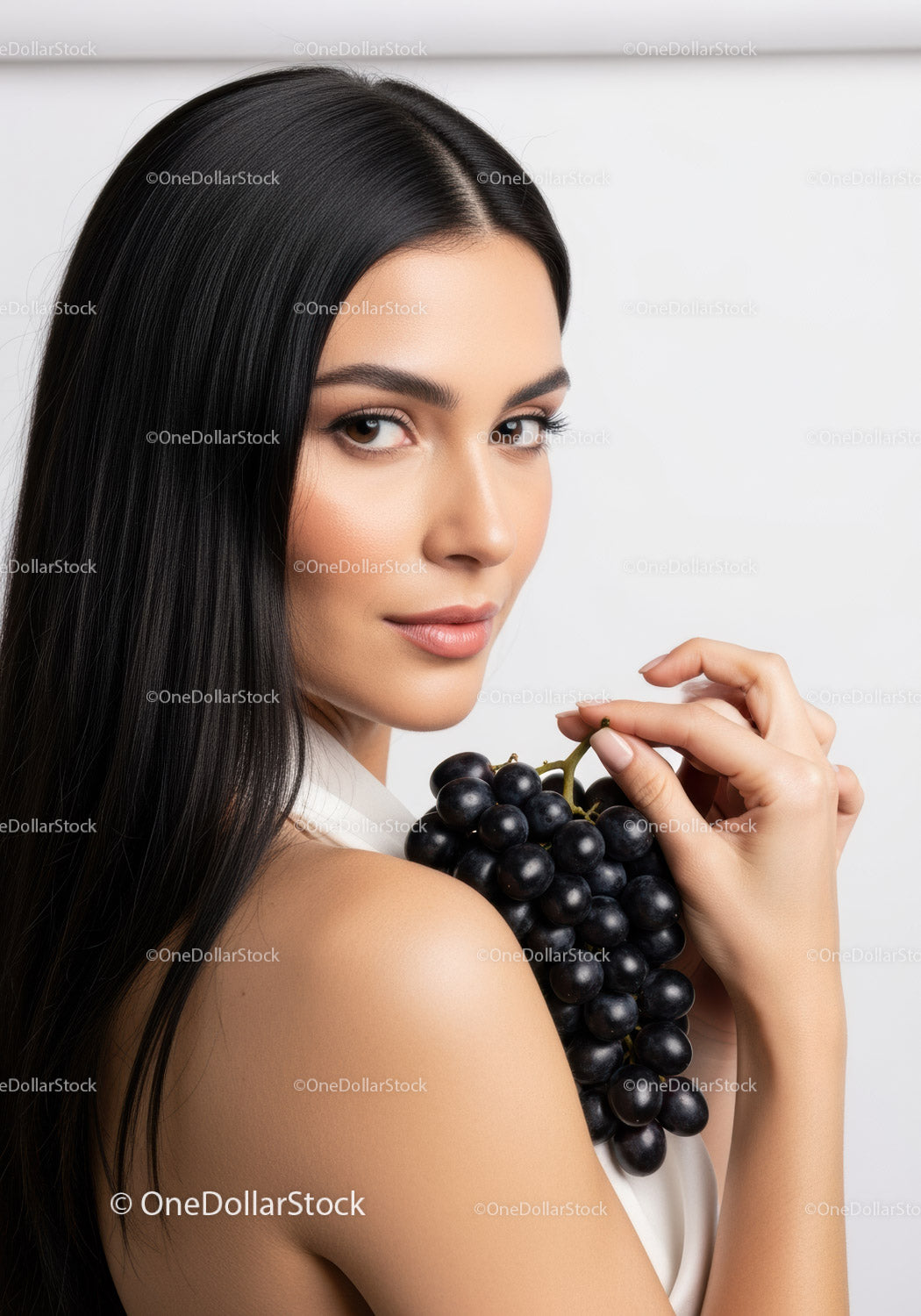 Elegant Woman Holding Bunch of Black Grapes in Bright Studio Light