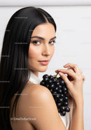 Elegant Woman Holding Bunch of Black Grapes in Bright Studio Light