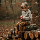 Child Sitting on Wood Logs Holding Red Apple
