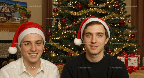 Two Young Men Wearing Santa Hats Near Christmas Tree