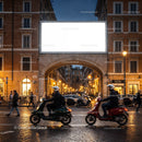 Evening scooter riders passing historic city archway