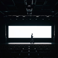 Businessman walking across empty theater stage with screen