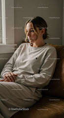 Woman in Beige Sweatshirt Relaxing Indoors by Window with Natural Light