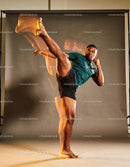 Young man performing a high martial arts kick indoors