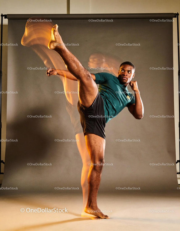 Young man performing a high martial arts kick indoors