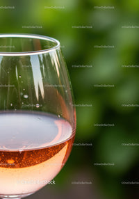 Close-up of rose wine glass with garden background