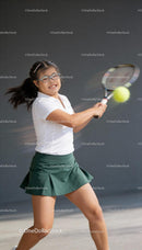 Young girl with glasses playing tennis with focused smile