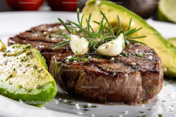 Juicy Grilled Steak with Fresh Avocado and Garlic on White Plate