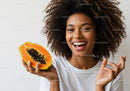 Joyful Woman with Fresh Papaya Fruit in Bright Studio Setting