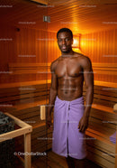 Young Man Relaxing in Wooden Sauna with Towel in Wellness Center