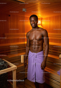 Young Man Relaxing in Wooden Sauna with Towel in Wellness Center