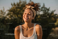 Joyful Young Woman with Curly Hair Smiling Outdoors in Summer