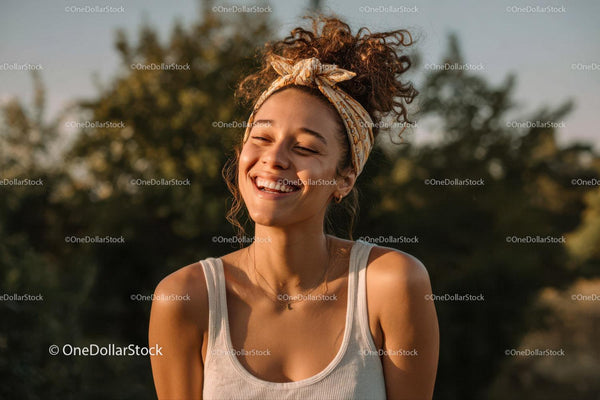 Joyful Young Woman with Curly Hair Smiling Outdoors in Summer