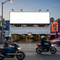 Motorcyclists passing by urban parking garage at dusk