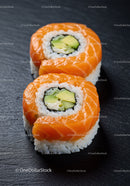 Fresh salmon avocado sushi rolls on black slate