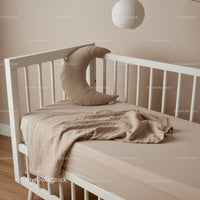 Cozy beige baby crib with crescent pillow and blanket