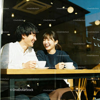 Happy young couple sharing coffee and laughter in cafe