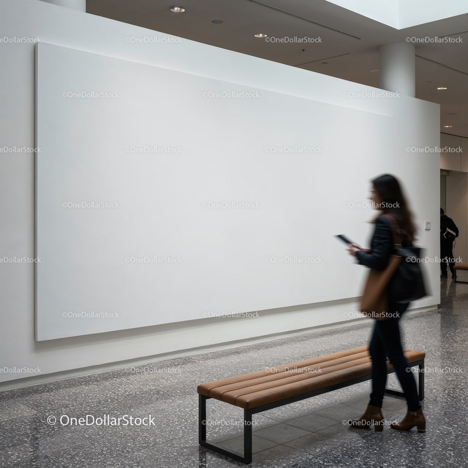 Woman walking past blank gallery wall with leather bench