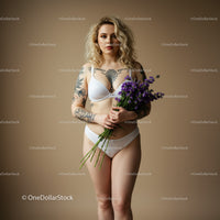 Elegant Tattooed Woman Holding Purple Flowers in Lingerie