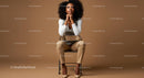 Thoughtful Woman Seated in Elegant Attire Against Brown Background