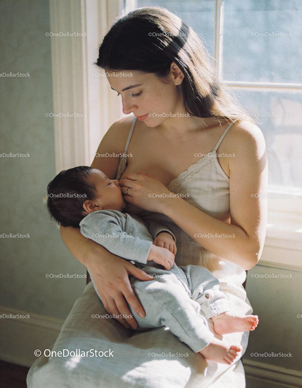 Mama pokojowo karmiąca piersią swojego śpiącego noworodka