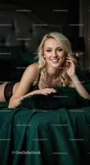 Smiling blonde woman relaxing on dark green bed