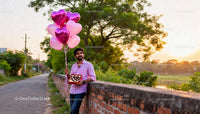 Man Holding Heart-Shaped Balloons and Chocolates Outdoors