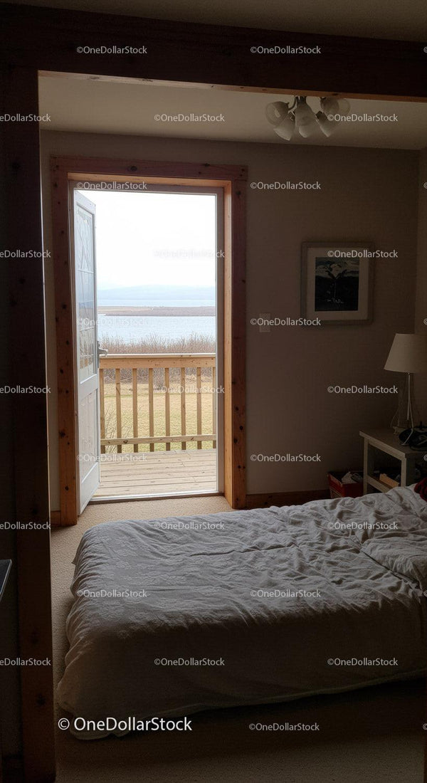 Spokojna sypialnia z widokiem na jezioro i drewnianymi drzwiami na balkon