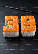 Fresh salmon avocado sushi rolls on black slate plate