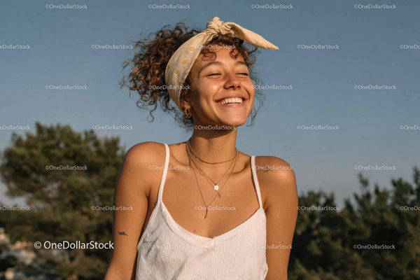Portrait of Joyful Woman with Curly Hair and Headscarf in Sun