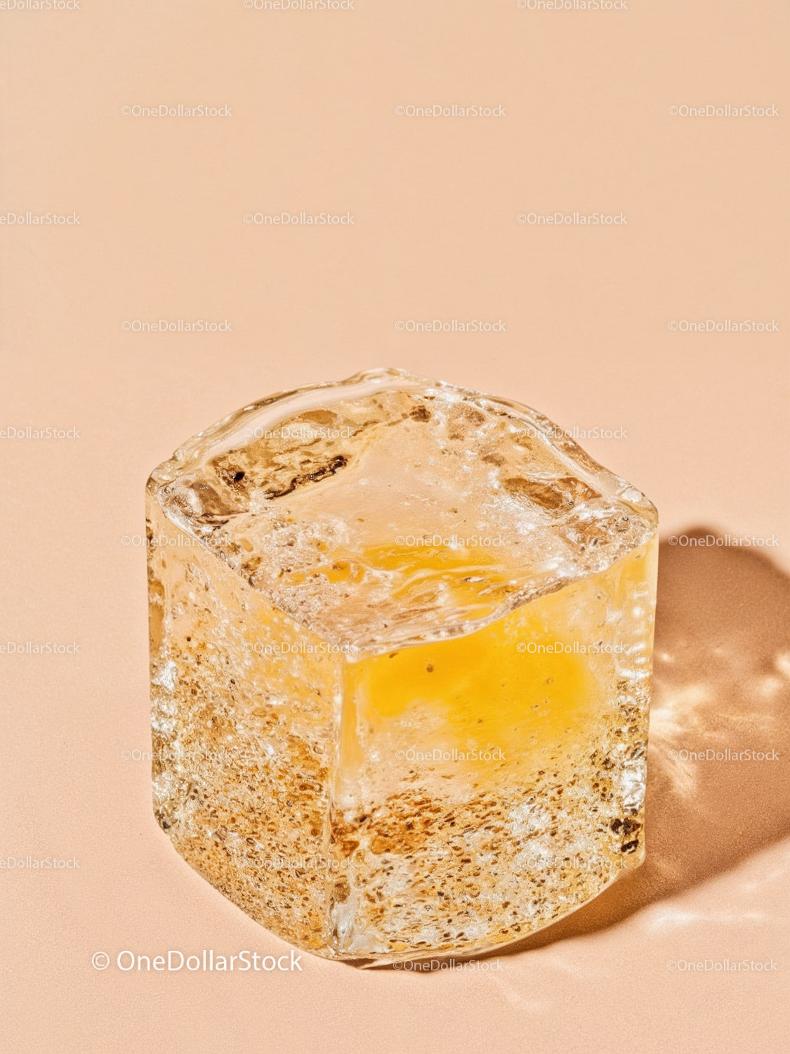 Close up of melting ice cube on warm beige surface