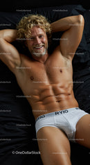 Smiling muscular man relaxing on black bed