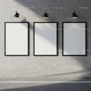 Three blank vertical posters on concrete wall under lights
