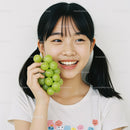 Girl Holding Green Grapes Smiling Brightly in Indoor Setting