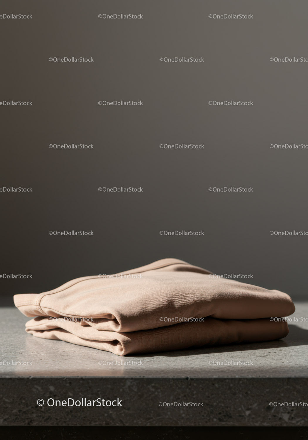 Minimalistyczny beżowy sweter złożony na betonowej powierzchni