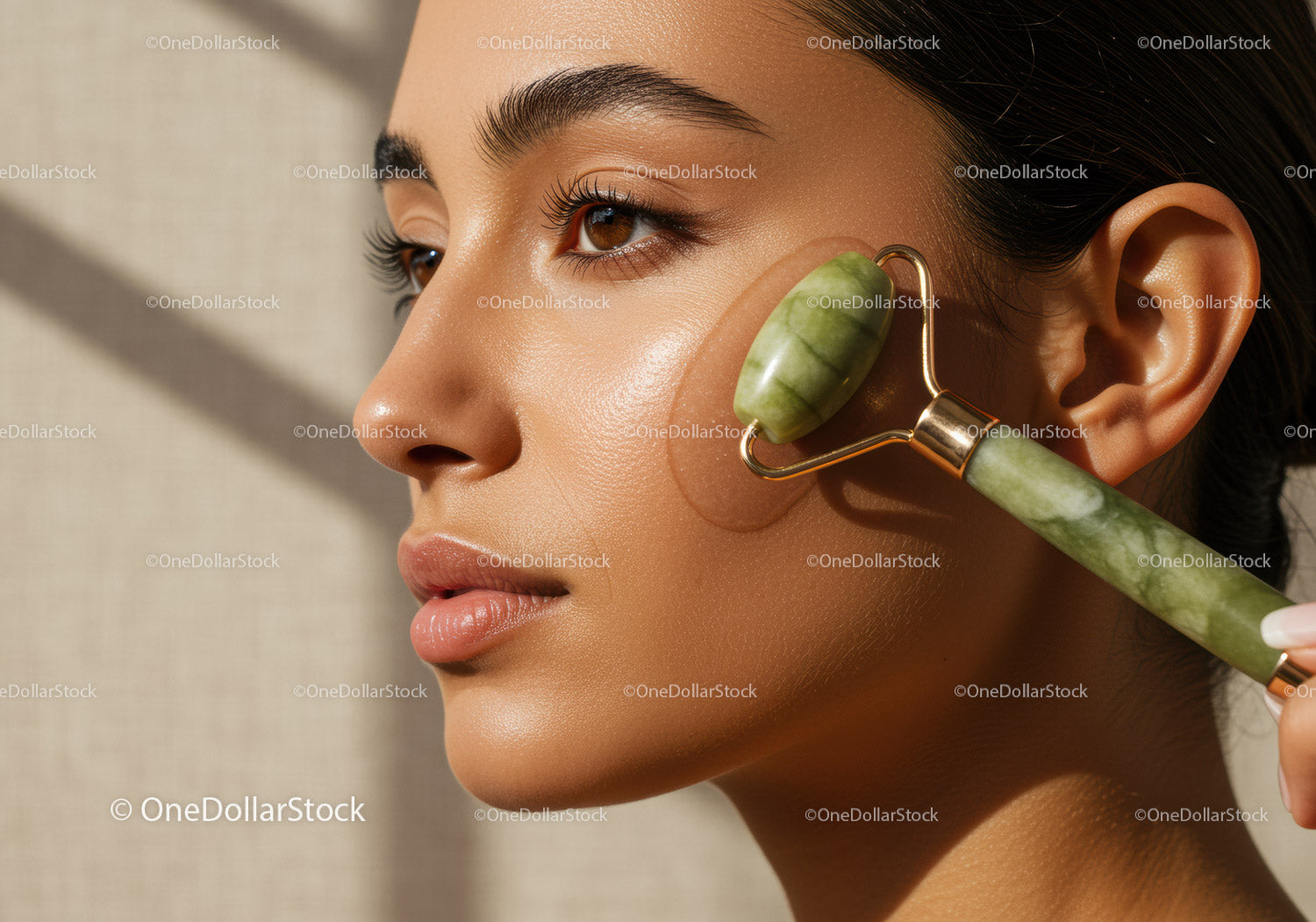 Młoda kobieta używa wałka jadeitowego do odmładzania skóry w salonie spa
