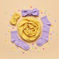 Pastel baby accessories with confetti on beige background