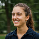 Close-Up of a Smiling Young Woman Outdoors Against Green Foliage