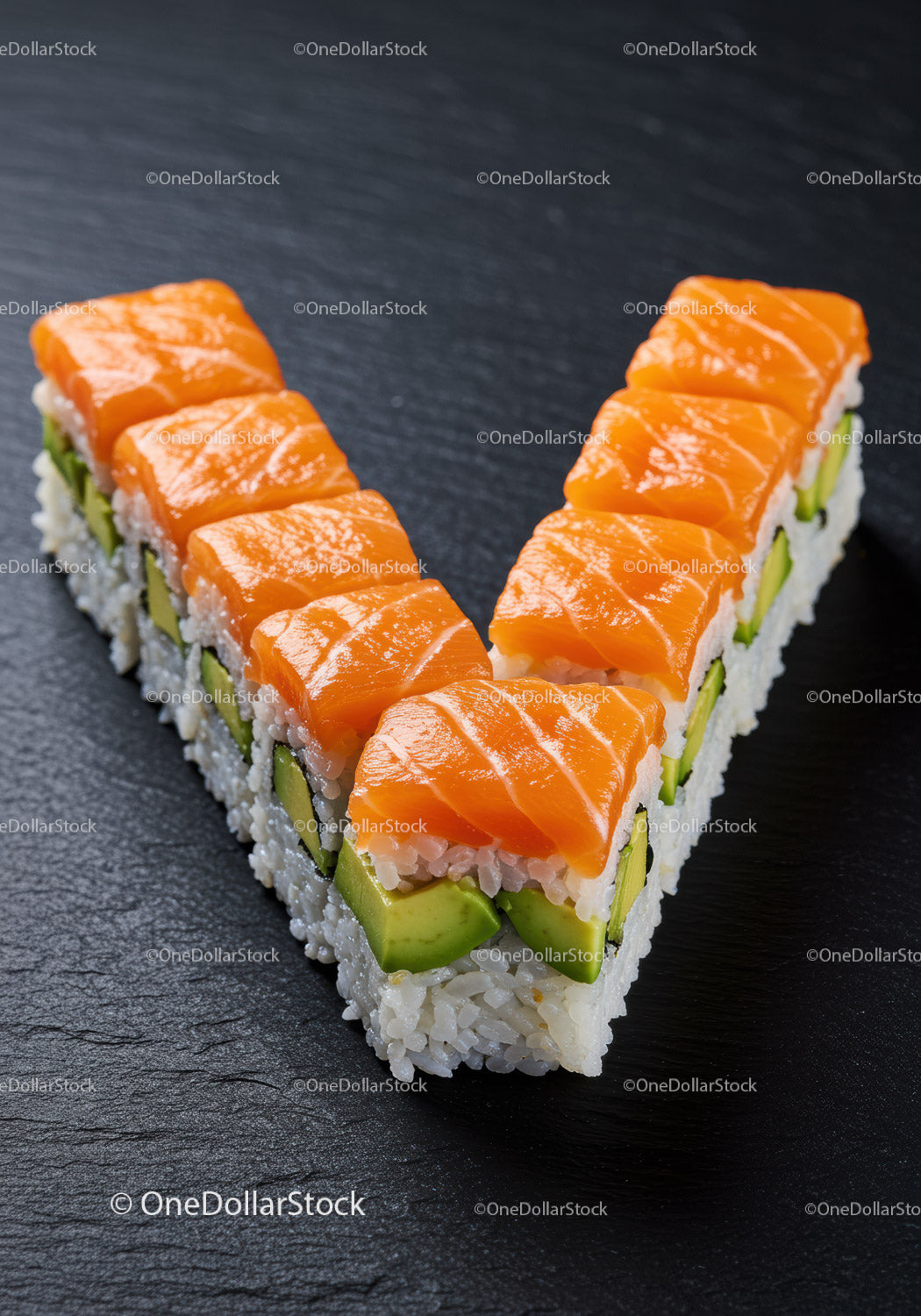 Świeże sushi z łososiem i awokado ułożone w kształcie litery V na łupku