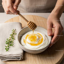Honey Dripping into Yogurt with Fresh Herbs on a Wooden Serving Board