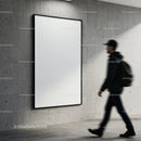 Man walking past blank poster on concrete wall